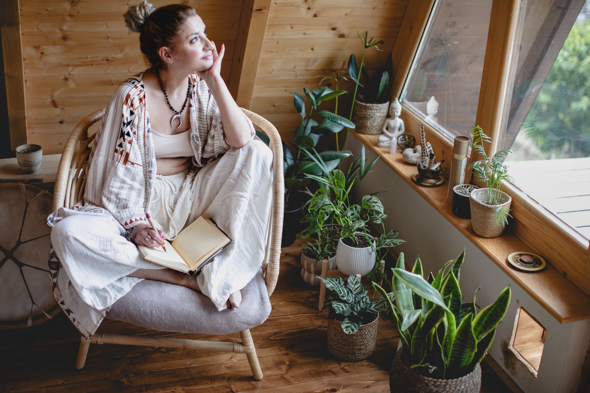 Young woman writing notein living room. Indoor lifestyle portrait. Self-care and mindfulness concept